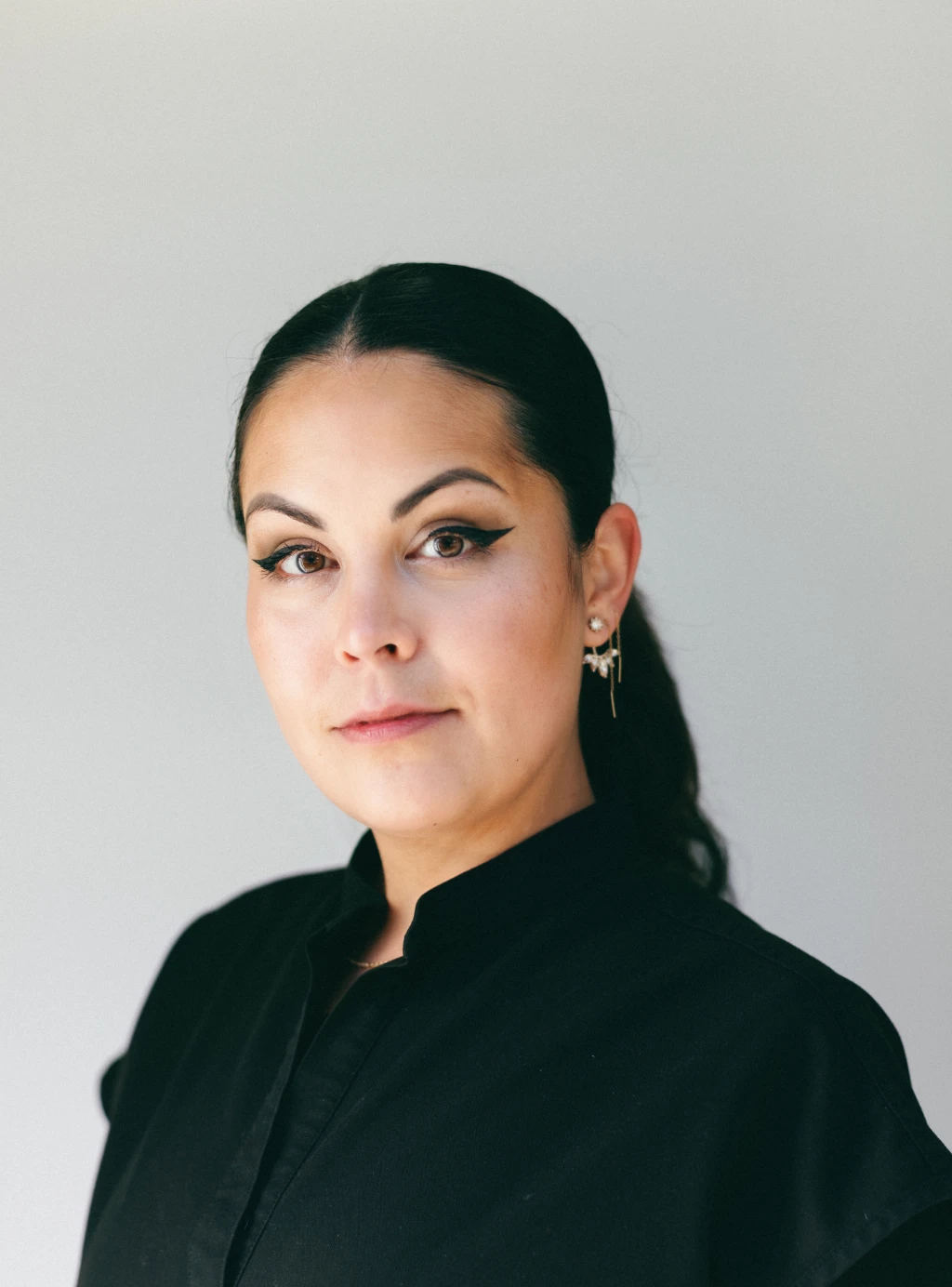 A woman in a black shirt flashing a dental smile while posing for a photo.