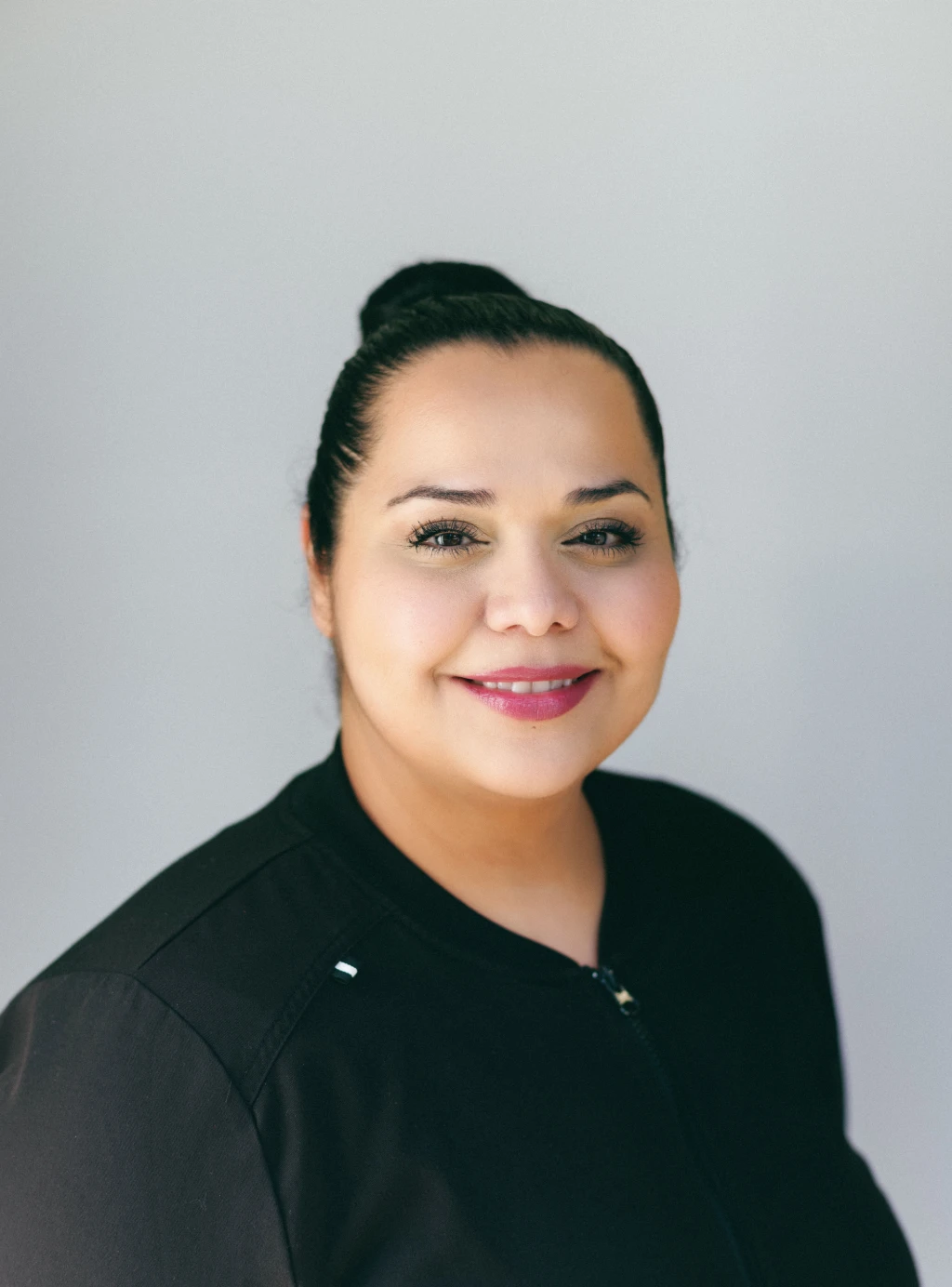 A woman in a black shirt smiling for the camera.
